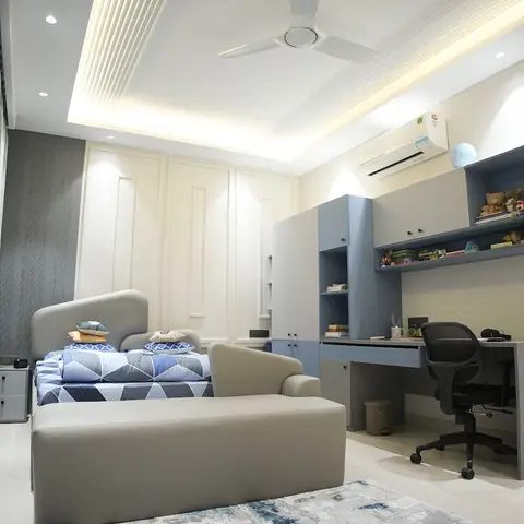 Kids bedroom with a grey study unit and open shelving displaying toys beside a single bed with geometric blue bedding