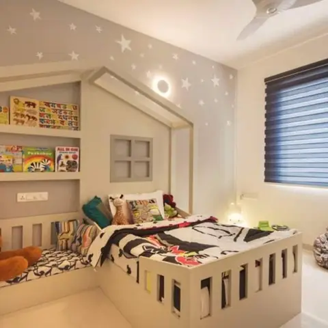 Kids' bedroom with a house-shaped built-in bed and bookshelf, a star-painted feature wall, and a teddy bear on the built-in window seat.