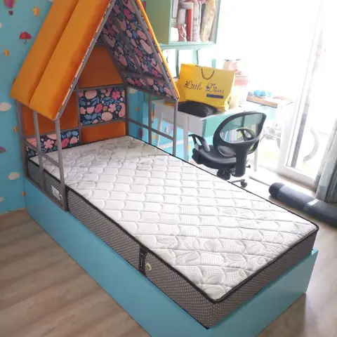 Kids' bedroom with a house-shaped canopy bed in orange padded velvet against a teal hot-air-balloon wallpaper wall, and a small study desk in the corner.