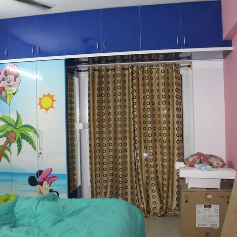 Kids bedroom with a Mickey-and-Minnie printed acrylic wardrobe shutter, blue loft cabinets above and a pink accent wall.