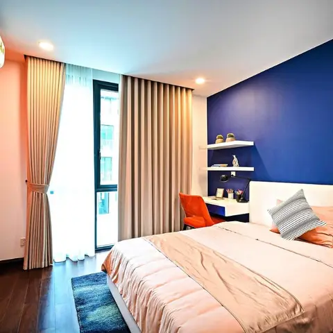 Kids bedroom with a navy accent wall behind the bed and an orange wall featuring a large basketball-themed mural beside a white floating study desk.