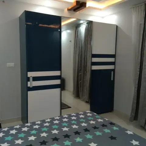 Kids' bedroom with a navy-and-white striped sliding wardrobe featuring a central mirror door, a star-print bedspread