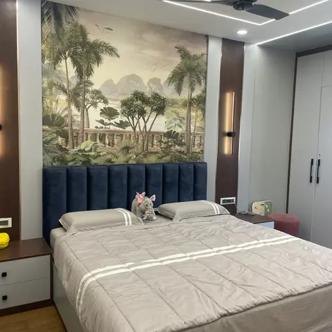 Kids' bedroom with a navy channel-tufted headboard beneath a tropical palm-scene wallpaper mural and a stuffed toy elephant on the bed.