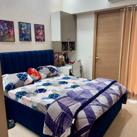 Kids' bedroom with a navy channel-tufted upholstered bed, a curated wall of anime posters, and a built-in study nook with an overhead storage cabinet.