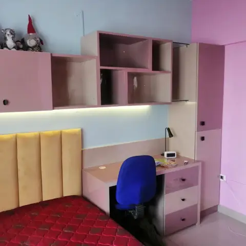 Kids' bedroom with a pink and cream study-and-wardrobe unit, open cubby shelving, a mustard channel-tufted headboard