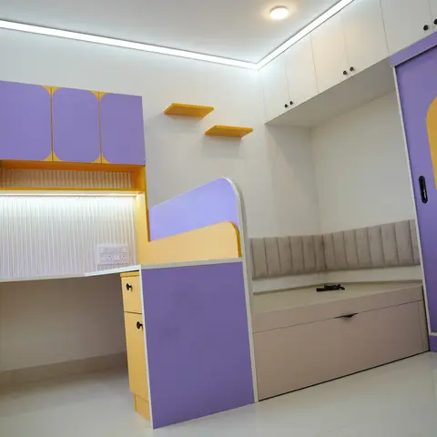 Kids' bedroom with a purple and yellow built-in study desk, sliding polka-dot wardrobe, and a cushioned platform bed with storage drawer.