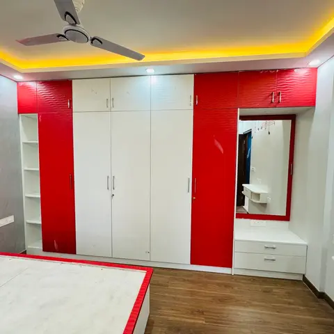 Kids bedroom with a red-and-white glossy wardrobe wall, matching red-trimmed bed and dresser mirror nook, and a musical-note wall decal