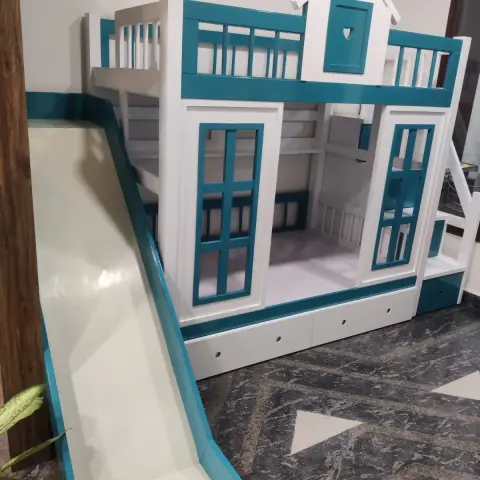 Kids' bedroom with a teal-and-white playhouse-themed bunk bed featuring a built-in slide, window cutout panels, and storage drawers underneath.