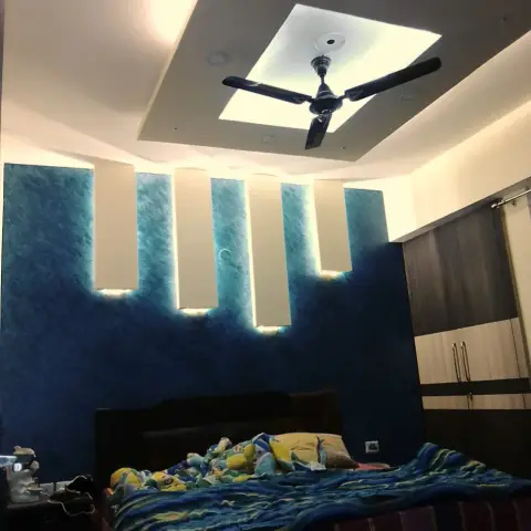 Kids' bedroom with a textured deep-teal accent wall, four backlit vertical panels, a stepped cove ceiling and a cartoon-print bedspread.