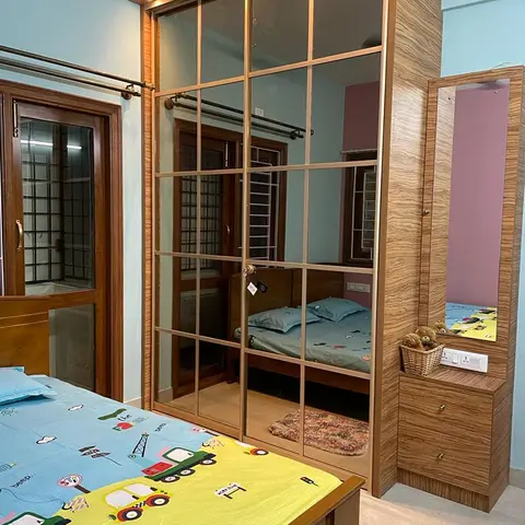 Kids' bedroom with a vehicle-print bedsheet, a mirrored sliding-door wardrobe with overhead lighting