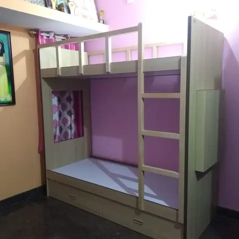 Kids' bedroom with a wood-laminate bunk bed with ladder and storage drawers, set against pink and orange painted walls with a framed family photo.