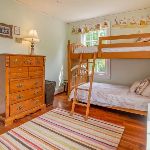 Kids bedroom with a wooden bunk bed and ladder, a striped rug and an alphabet bunting garland over the window
