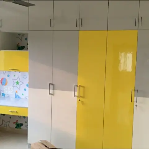 Kids' bedroom with a yellow and grey gloss-laminate wardrobe wall and a built-in study nook featuring a star-patterned wallpaper backdrop.