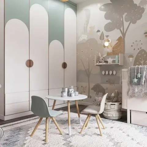 Kids' bedroom with an arched sage-and-white wardrobe, a woodland-mural accent wall, a round kids' play table with pastel chairs