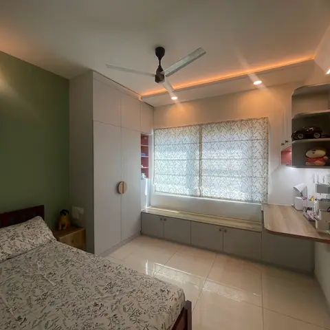 Kids' bedroom with an olive-green accent wall, a white wardrobe with a wood dot handle, a built-in window seat bench