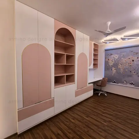 Kids' bedroom with arched pink-and-white wardrobe doors, open display shelving, and a built-in study desk under a world map wallcovering