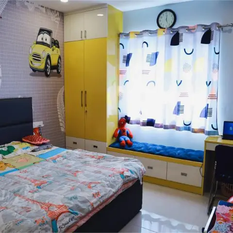 Kids' bedroom with car-themed wallpaper, a yellow built-in wardrobe and study desk, and a cushioned window seat.