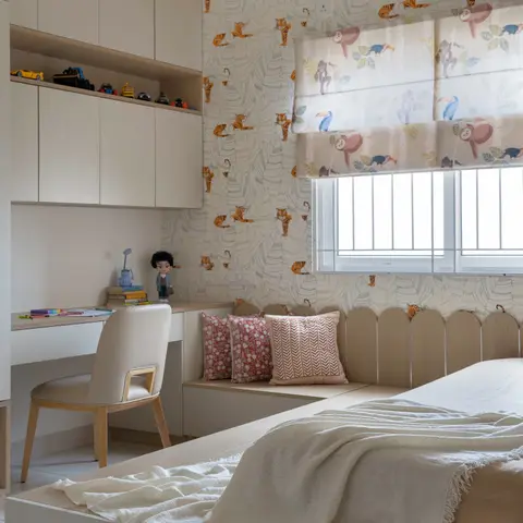 Kids' bedroom with jungle-animal wallpaper and a matching roman blind, a built-in window seat with cushions, and a study nook styled with toy cars.