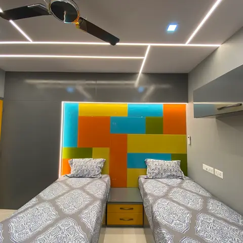 Kids bedroom with twin beds flanking a colour-blocked orange, teal, yellow and green headboard wall panel, and a yellow glossy wardrobe.