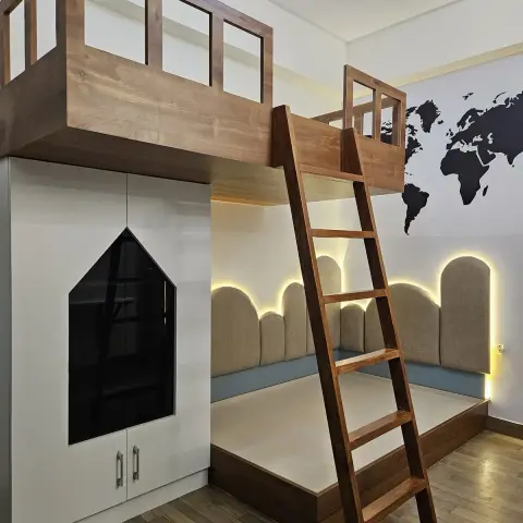 Kids' loft bed with a wooden treehouse-style railing and ladder above a cushioned daybed nook