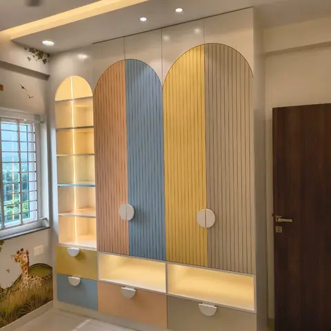 Kids' room wardrobe with arched multicolour fluted shutters in blush, blue, yellow and grey, an open backlit display shelf beside it