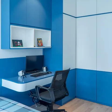 Kids' room with a bold blue-and-white built-in study desk under an open display shelf holding comic books and toys