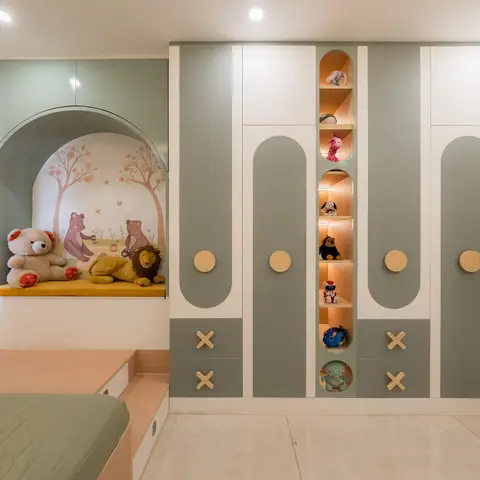 Kids' room with a sage-green and white wardrobe featuring wood-disc pulls and a backlit toy display niche