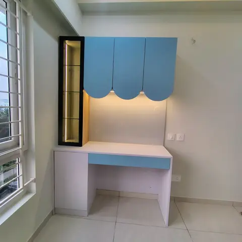 Kids' room with a scalloped sky-blue study-desk unit and a backlit glass display niche beside the window