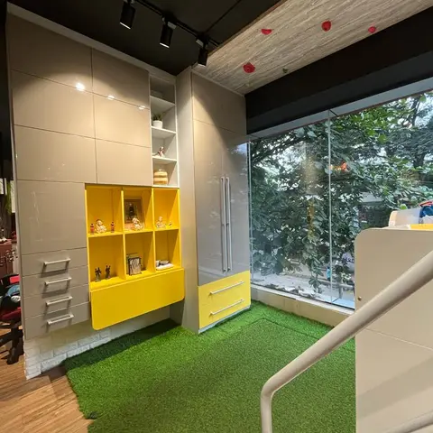 Kids room with a yellow display shelf of collectible figurines, grey wardrobe, artificial-turf flooring