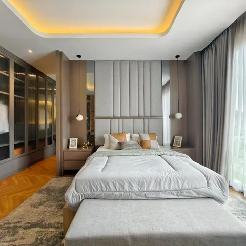 King bed with a channel-tufted grey upholstered headboard wall flanked by pendant lights