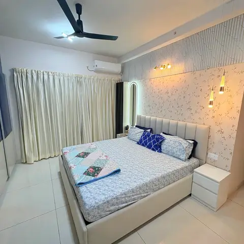 King bed with a channel-tufted headboard against a floral-wallpaper accent wall strung with drop pendants, a glossy navy wardrobe on the opposite side.