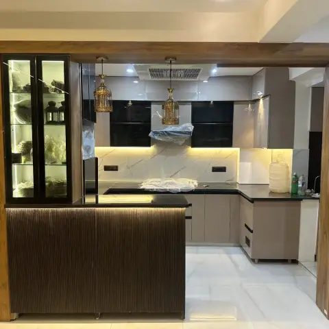 Kitchen at handover stage with a fluted-wood breakfast counter, a glass display cabinet, black stone counters, and gold cage pendant lighting