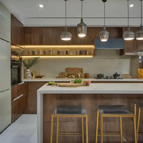 Kitchen island in dark walnut cabinetry with a white stone waterfall countertop, gold-framed bar stools, and a cluster of textured glass pendant lights
