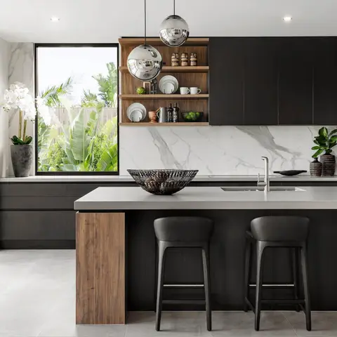 Kitchen island in matte black handleless cabinetry with a wood-clad end panel, a book-matched marble slab backsplash