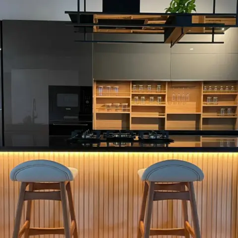 Kitchen island with a black granite countertop, built-in gas hob, backlit fluted wood island front
