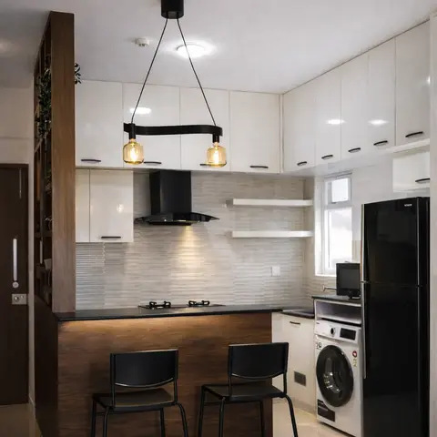 Kitchen with a black chimney hood over a black-countertop island, wood-panel island front, dual pendant lighting