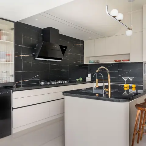 Kitchen with a black marble waterfall-veined backsplash, cream flat-panel cabinetry