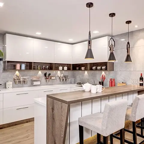Kitchen with a white gloss L-shaped run and a central island breakfast bar topped in wood, three black pendant lights above, grey stone-effect walls