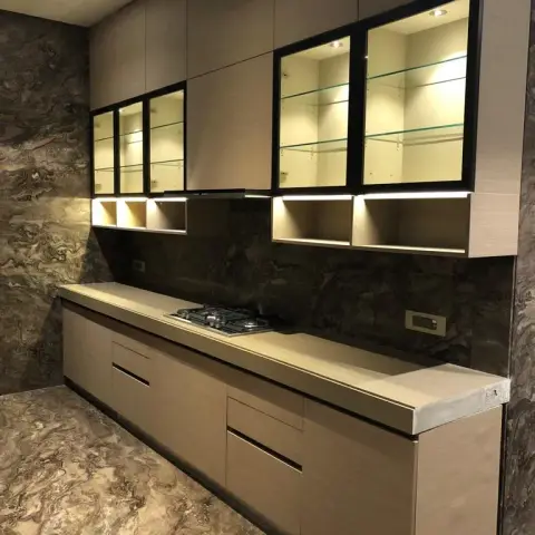 Kitchen with dramatic book-matched brown marble wall cladding and backsplash, glass-front upper cabinets lit with internal LED shelving