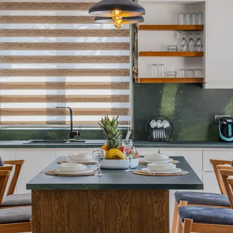 Kitchen with white cabinetry, a green marble backsplash and countertop, a matte-black tap, open wood shelving with glassware