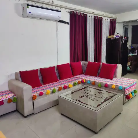 L-shaped grey sectional sofa dressed with red cushions and a colourful tasselled runner