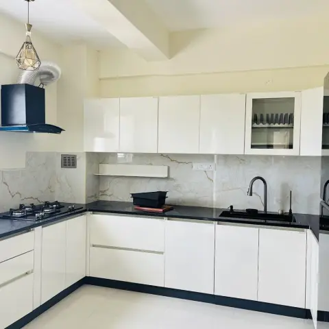 L-shaped ivory high-gloss kitchen with J-profile drawers, a black granite counter