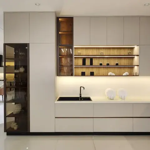 L-shaped kitchen in handleless greige matt shutters run floor to ceiling, with a smoked-glass crockery column