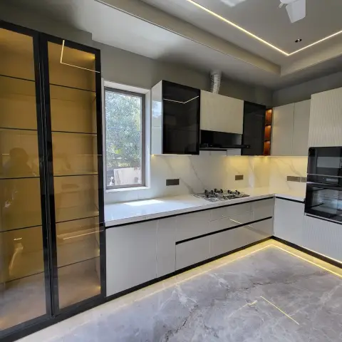 L-shaped kitchen in pale grey handleless shutters with black-glass wall units over the hob, a statuario slab backsplash