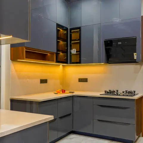L-shaped kitchen with glossy grey cabinets, a backlit glass-shutter display unit, marble countertop and backsplash