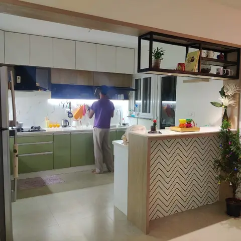L-shaped kitchen with olive-green glossy lower cabinets and white uppers, a chevron-patterned breakfast counter facade