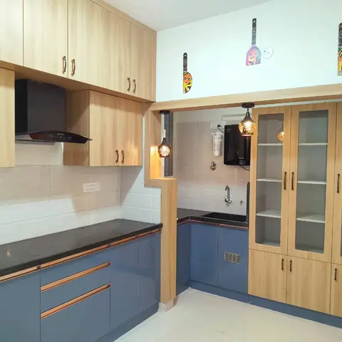 L-shaped kitchen with slate-blue cabinetry trimmed in copper, a black granite counter, a glass-front crockery display unit, pendant lighting