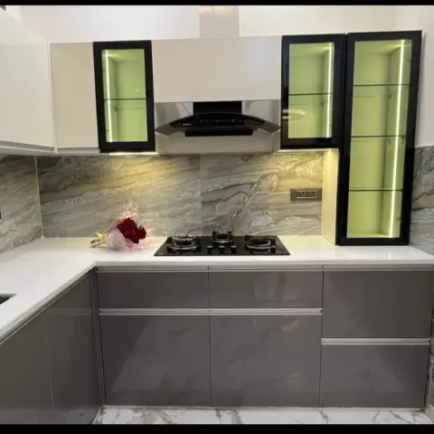 L-shaped kitchen with taupe-grey gloss base units under a white quartz counter, ivory wall units, grey veined marble dado slabs