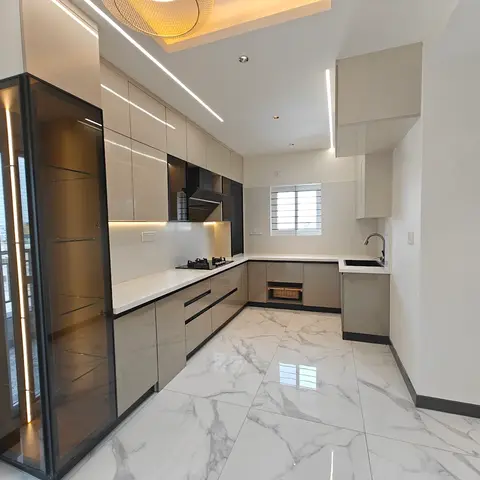 L-shaped modular kitchen with glossy mocha shutters, a white quartz countertop, a tall glass-front crockery display unit