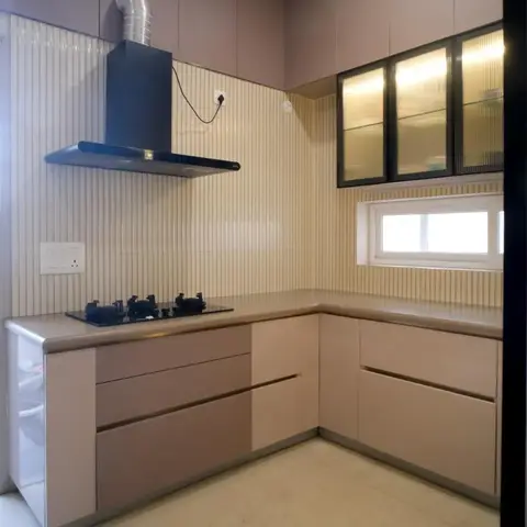 L-shaped modular kitchen with handleless dusty-mauve shutters, a black chimney hood over the hob, ribbed cream tile backsplash